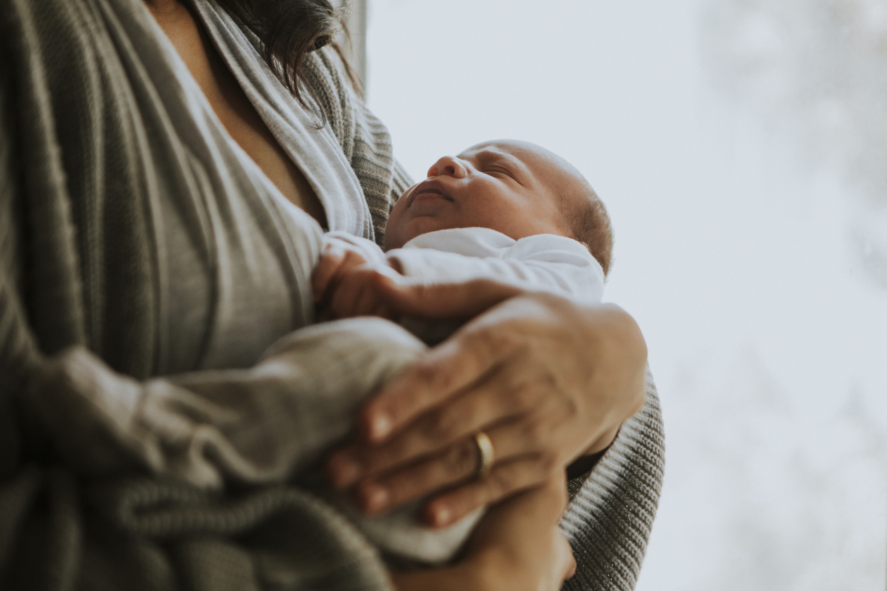 Mother holding her baby indoors.